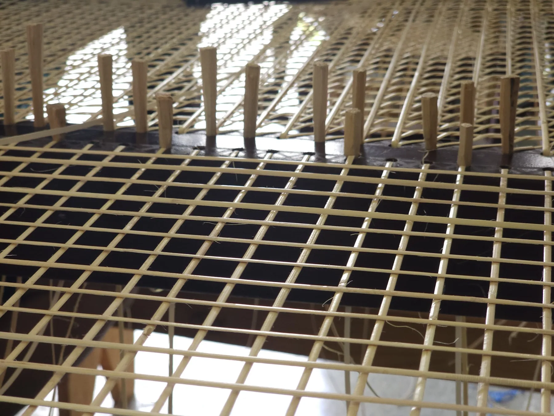 Cane weave being assembled on a chair frame